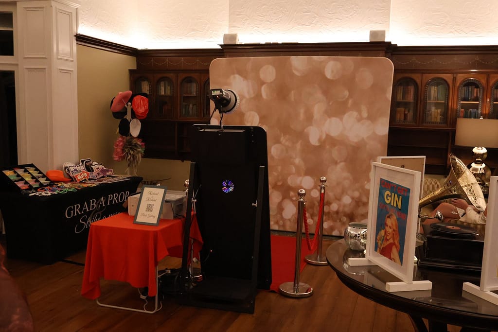 Wards Photo Booths full setup in the oak-panelled Morning Room at Pendrell Hall, featuring a gold backdrop, red carpet, and prop table.