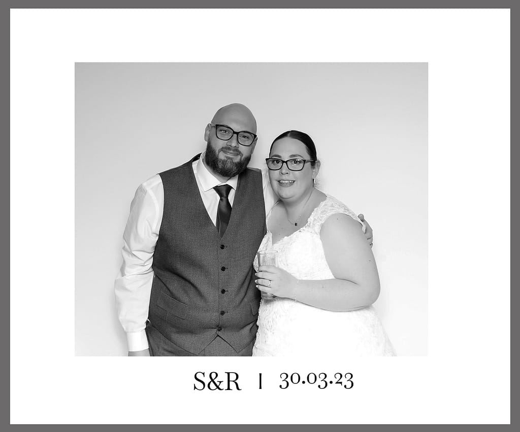 A professional black and white photo booth print featuring a bride and groom, with a personalized footer showing their initials "S&R" and the wedding date "30.03.23"